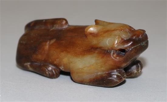 A Chinese yellow and brown jade figure of a recumbent of a lion dog, Ming dynasty or earlier, 5.7cm, calcification